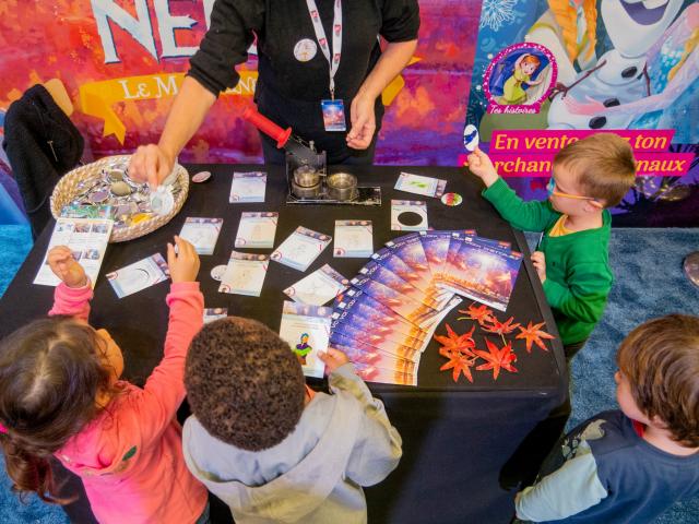 Foto van kinderen spelend met kaarten en tijdschriften op een tafel tijdens het Voix d'Etoiles festival in Port Leucate